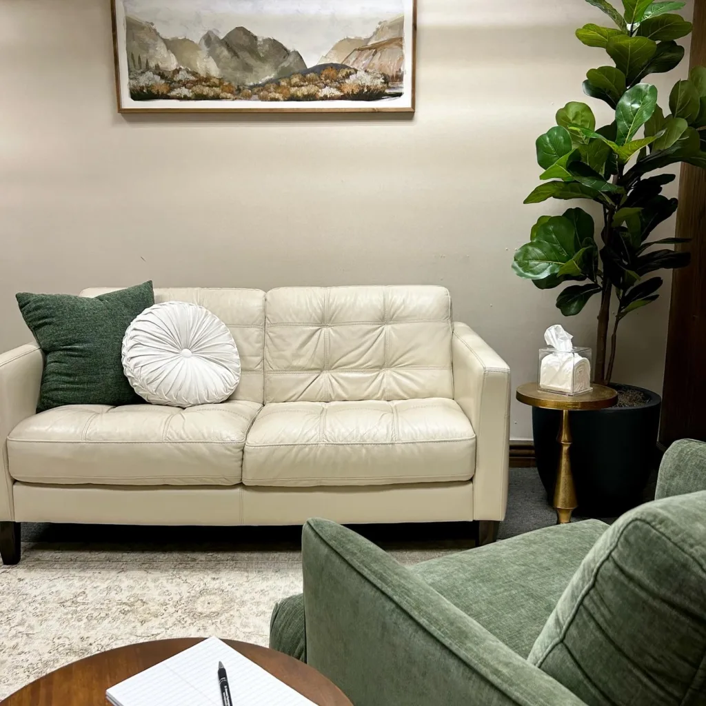 Therapy room including white sofa and green therapist chair.