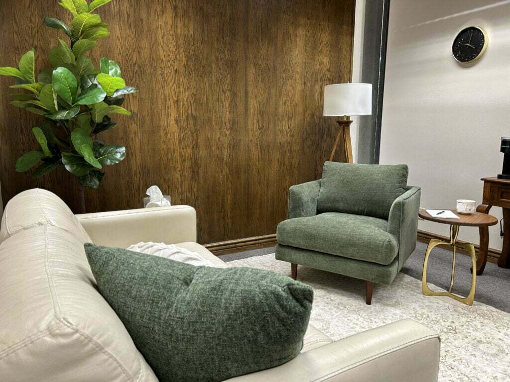 Image of therapy room including green therapist chair with white client sofa